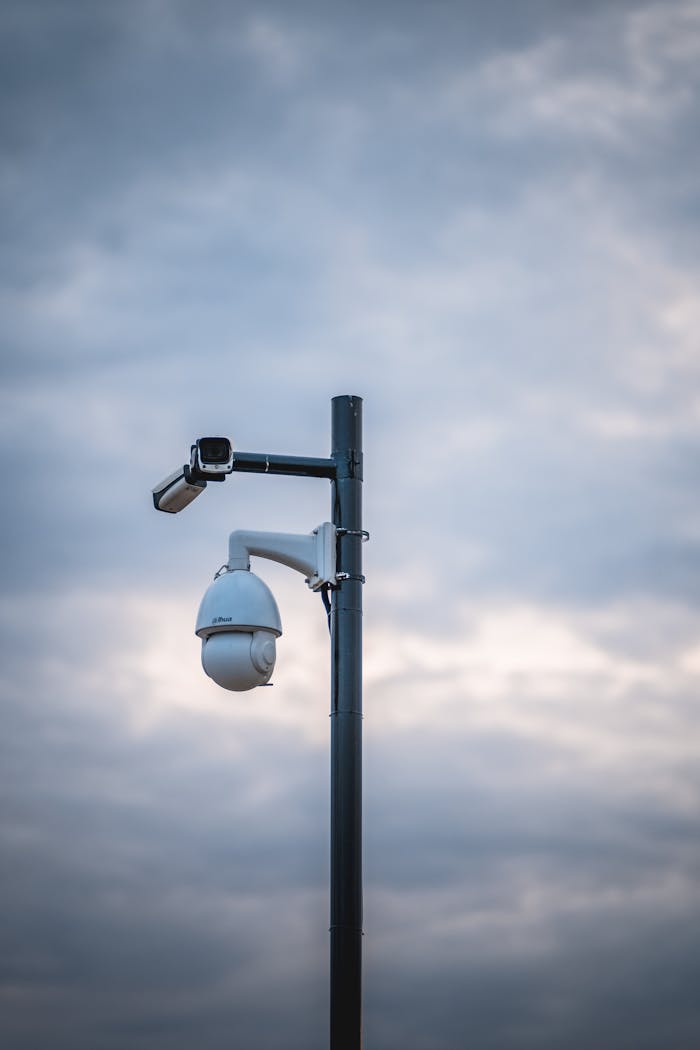 gallery-2 Security cameras mounted on a pole under a cloudy sky emphasize surveillance and protection.
