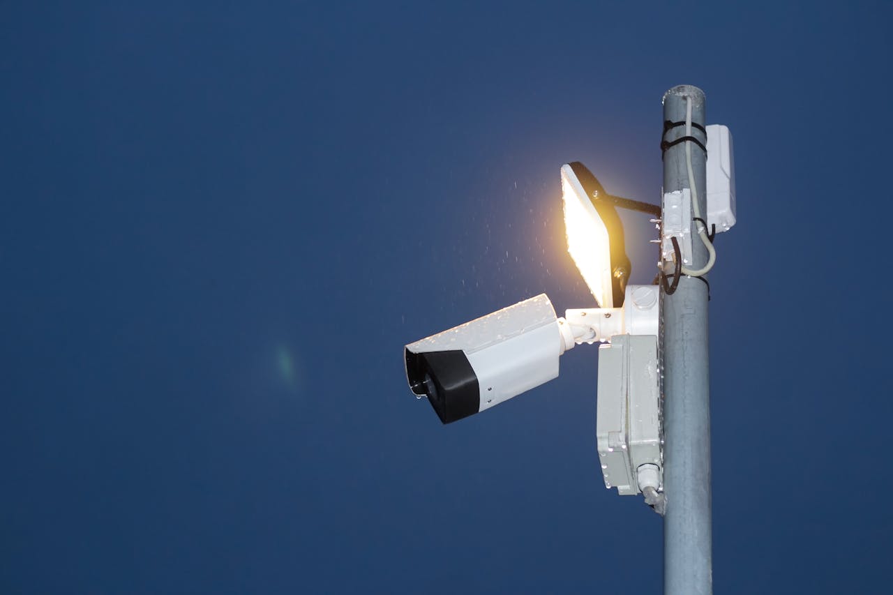 hero-img-01 Low angle view of a security camera and light against a dark blue night sky.
